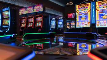 Vista della moderna area slot machine del Casinò Admiral Triesen con slot machine illuminate a colori.