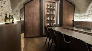 Elegante sala degustazione dell'WY Weinbar con soffitto a volta ed elegante tavolo in legno per esclusive degustazioni di vino.