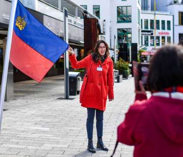 La guida cittadina presenta la bandiera del Liechtenstein durante una visita guidata nel centro di Vaduz
