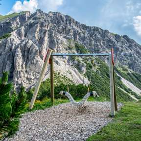 Altalena sospesa sul sentiero delle altalene Malbun con vista sulle ripide pareti rocciose e sul paesaggio alpino in Liechtenstein