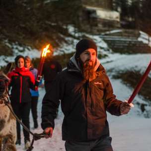 Gruppo in escursione guidata con i lama nel Liechtenstein innevato con le torce - suggestiva avventura all'aria aperta per grandi e piccini.