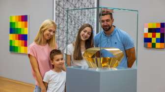 Una famiglia osserva una scultura d'oro nel museo d’arte del Liechtenstein - arte per grandi e piccini nel cuore di Vaduz.