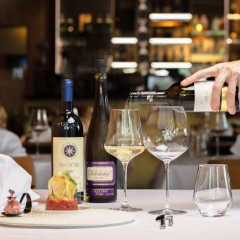 Un cameriere versa del vino bianco per accompagnare un piatto elegantemente servito nel ristorante Alpspitz.