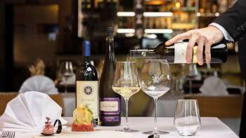 Un cameriere versa del vino bianco per accompagnare un piatto elegantemente servito nel ristorante Alpspitz.