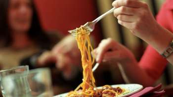 Una persona raccoglie gli spaghetti con una forchetta da un piatto nella Brasserie Burg