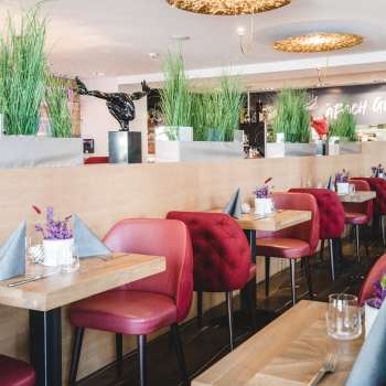 : Tavoli generosamente disposti nel PUR Restaurant & Bar con sedie rosse e decorazioni floreali.
