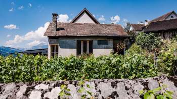 Casa tradizionale del ristorante Torkel, circondata da vigneti con vista sulle Alpi.