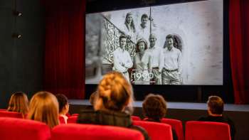 I visitatori siedono in una sala rossa del vecchio cinema di Vaduz e guardano un film storico sul Liechtenstein.