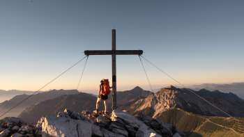 Escursionista presso la croce di vetta sul monte Augstenberg