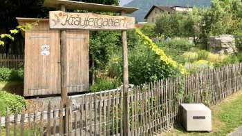 Cartello in legno con la scritta "Kräutergarten" (giardino delle erbe) all'ingresso del giardino curato a Mauren, circondato dalla natura e dalle montagne. Cartello in legno con la scritta "Kräutergarten" (giardino delle erbe) all'ingresso del giardino curato a Mauren, circondato dalla natura e dalle montagne.