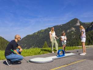 Una famiglia si gode una partita di minigolf nella soleggiata Malbun, nel Liechtenstein, circondata dal verde paesaggio alpino e dalle montagne in estate.