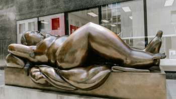 Voluttuosa figura femminile in bronzo - l'opera d'arte "Donna reclinata" di Fernando Botero è un'attrazione nel centro della città.