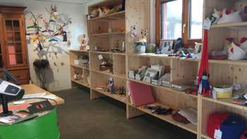Interno della Birkahoflädile con scaffali in legno pieni di prodotti regionali, decorati con elementi colorati - negozio di fattoria in Liechtenstein.