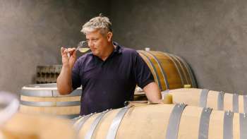 L'enologo della cantina Hoop in Liechtenstein degusta il vino direttamente dalla botte di legno nella cantina.