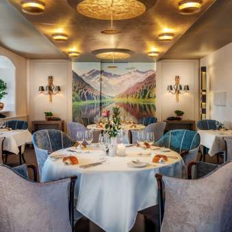 Tavoli rotondi con bicchieri da vino e candele nell'elegante sala da pranzo del Park Hotel Sonnenhof di Vaduz, Liechtenstein