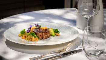 Squisito secondo piatto con carne succulenta, verdure fresche e fiori decorativi