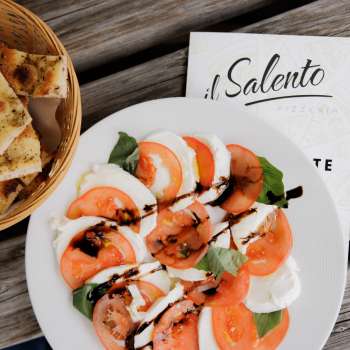 Pizza fresca con salsa di pomodoro e rucola, servita su un tavolo di legno rustico