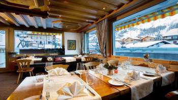 Sala da pranzo luminosa e invitante con ampie finestre e vista sulle montagne innevate