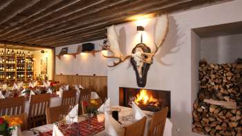 Ambiente accogliente del ristorante con travi di legno rustiche e camino