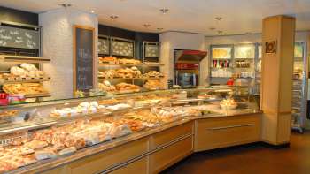 Vista della sala vendite della panetteria e pasticceria Amann con un bancone pieno e tante prelibatezze