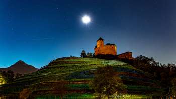 La Rocca di Gutenberg illuminata di notte, con la luna piena, immersa nei vigneti