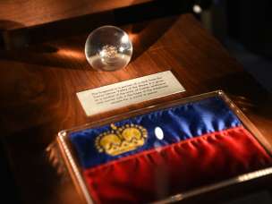 Mostra nella Camera del Tesoro del Liechtenstein: bandiera del Liechtenstein con corona d'oro e globo di vetro con manufatto storico