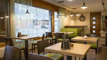 Un bistrot moderno con un ambiente accogliente, tavoli in legno e panche verdi alla moda
