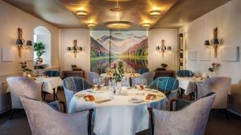 Elegante sala da pranzo con tavoli apparecchiati con stile, ambiente elegante e grande quadro paesaggistico