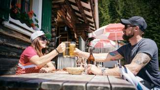 Due persone sorseggiano bicchieri di birra davanti al rifugio Gafadurahütte nelle Alpi del Liechtenstein