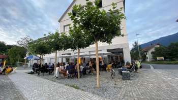 La vivace terrazza del St. Martins Pub am Platz con alberi ombrosi e ospiti ai tavoli