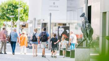 Le persone passeggiano nella moderna zona pedonale di Vaduz passando davanti al museo d'arte