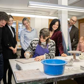 Un gruppo di visitatori interessati assiste alla modellazione di un vasaio: un'esperienza creativa in un'atmosfera accogliente presso il laboratorio di ceramica Schädler di Nendeln.