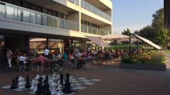 Terrazza solarium ben frequentata di un moderno ristorante con un grande campo da scacchi all'aperto