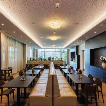 Luminosa sala da pranzo del ristorante Kommod con design elegante e grandi finestre.