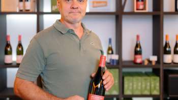 Harry Zech presenta una bottiglia del suo vino nell'elegante sala vendite - cultura vinicola regionale del Liechtenstein.