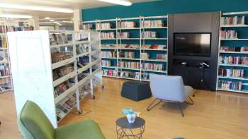 Accogliente angolo di lettura nella Biblioteca Nazionale del Liechtenstein con poltrone e parete multimediale tra alte librerie