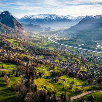 Una vista mozzafiato dalla collina sulla valle del Reno con campi, villaggi e montagne innevate: un idillio naturale nel Liechtenstein.