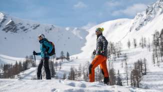 Due persone che fanno escursioni invernali attraverso il paesaggio innevato di Malbun con le montagne innevate sullo sfondo