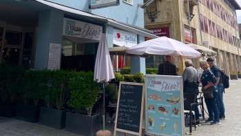 Vista esterna del ristorante Elisa con ombrelloni e menu esposto su una lavagna