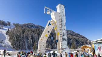 La torre di arrampicata ghiacciata di Malbun, circondata da ospiti invernali sullo sfondo alpino: un'attrazione per gli appassionati di sport invernali nel Liechtenstein.