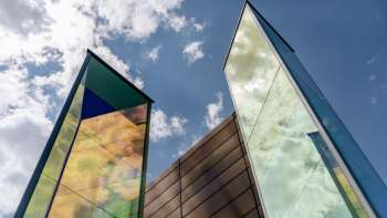 Installazione artistica "Two Light Prisms" di Heinz Mack con superfici di vetro colorate e scintillanti contro un cielo blu.