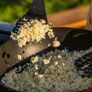 Preparazione del Rebel, piatto tradizionale di semolino del Liechtenstein, con spatole su una padella aperta