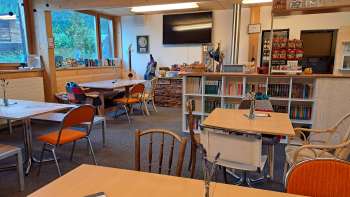 Vista della sala da pranzo con parete in legno e decorazione murale - diversi tavoli con posti a sedere e vista della parete decorativa con chitarre e immagini verdi.