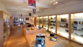 Vista su una luminosa sala espositiva del Museo Lawena con vetrine illuminate piene di apparecchi elettrici storici.