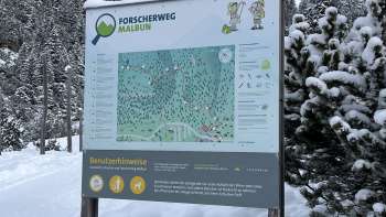 Ragazza con cappello verde guarda attraverso un telescopio sul Sentiero degli esploratori di Malbun con vista panoramica sulle Alpi del Liechtenstein.