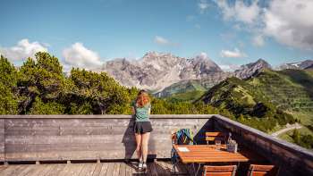 Donna che si gode la vista panoramica delle montagne circostanti dalla terrazza del ristorante di montagna Sareis