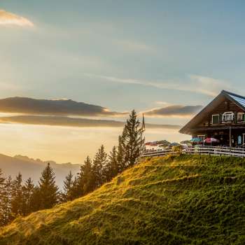 Rifugio Gadafura su un prato di montagna soleggiato con vista sulle montagne e sul tramonto