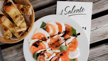 Pizza fresca con salsa di pomodoro e rucola, servita su un tavolo di legno rustico