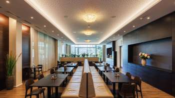 Luminosa sala da pranzo del ristorante Kommod con design elegante e grandi finestre.