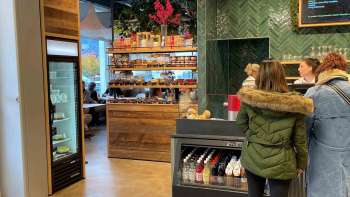 Clienti alla cassa, circondati da invitanti decorazioni in legno e prodotti freschi